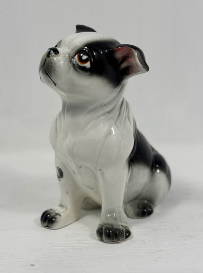 Ceramic figurine of a black and white dog on a light gray background