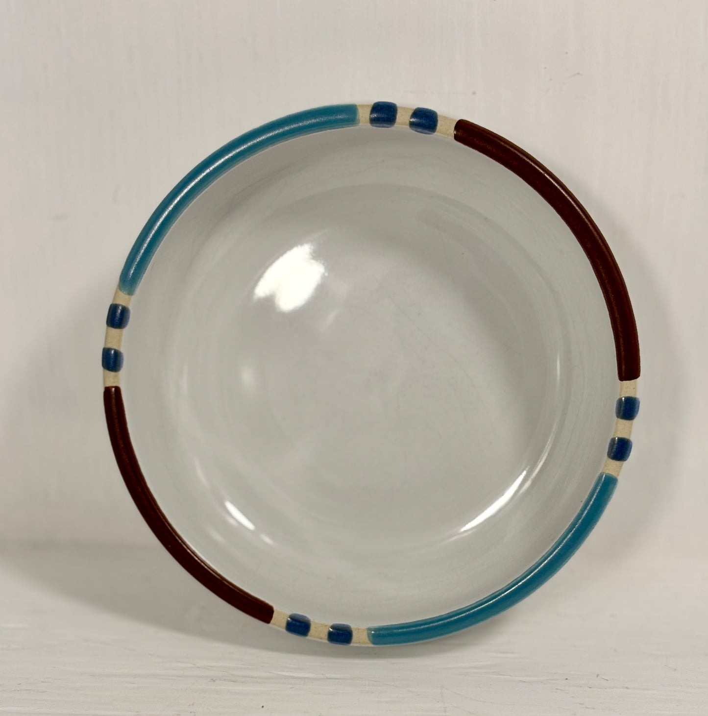 Ceramic bowl with blue and brown rim on a white background