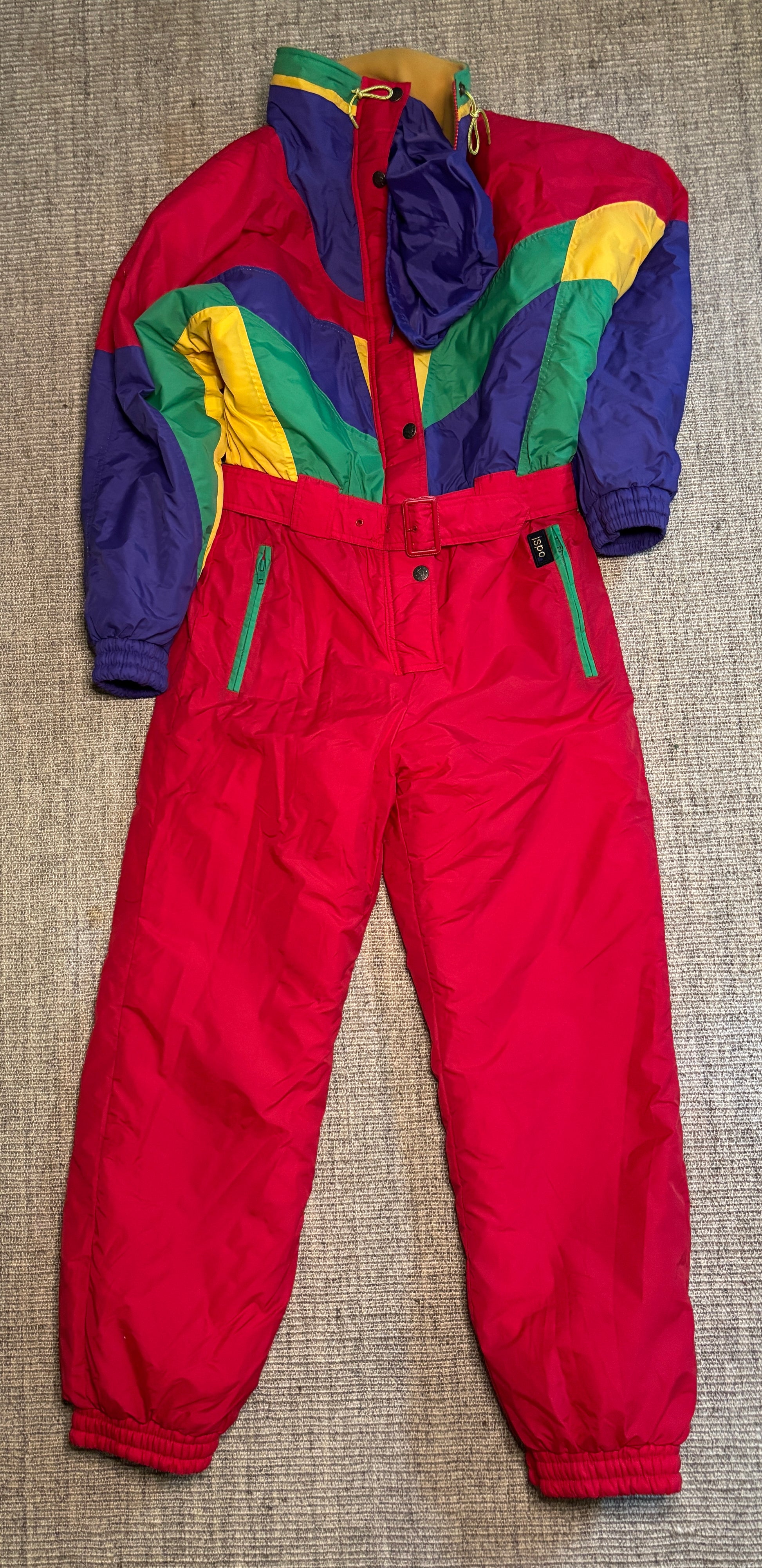 Colorful snowsuit with red pants and multicolored jacket on a textured surface