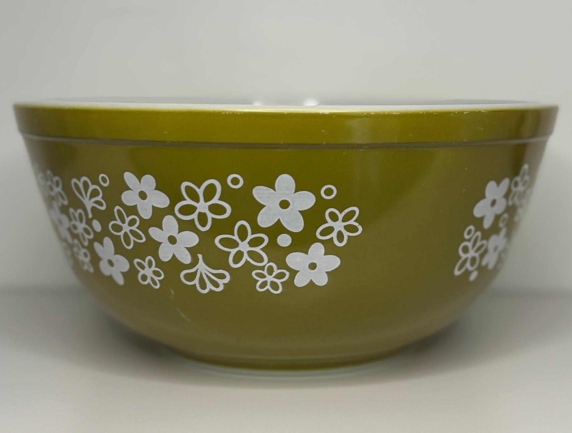 Green bowl with white floral pattern on a white background