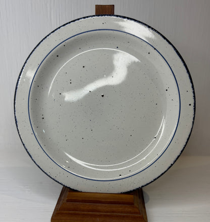 Speckled ceramic plate on a wooden stand against a white background