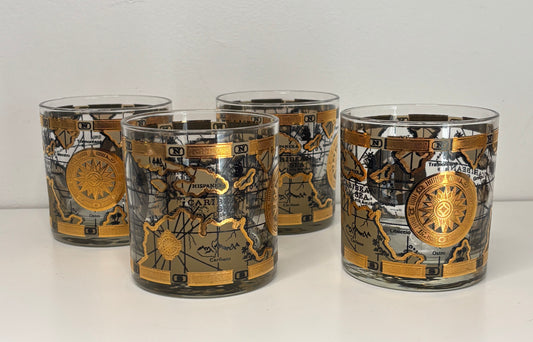 Set of four glass tumblers with astrological design on a white surface