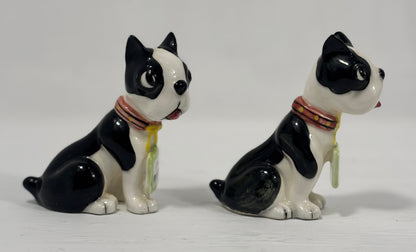 Two ceramic dog figurines with black and white color pattern on a white background