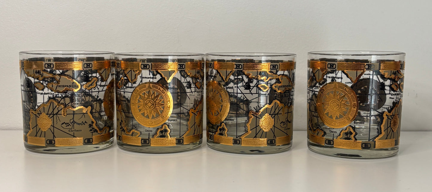 Set of four cylindrical candles with decorative labels on a white surface.