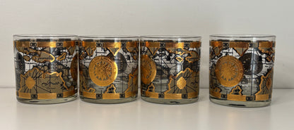 Set of four cylindrical candles with decorative labels on a white surface.