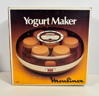 Vintage Moulinex Yogurt Maker retail box, showing the circular yogurt maker with several jars inside through a clear window, on a white background.