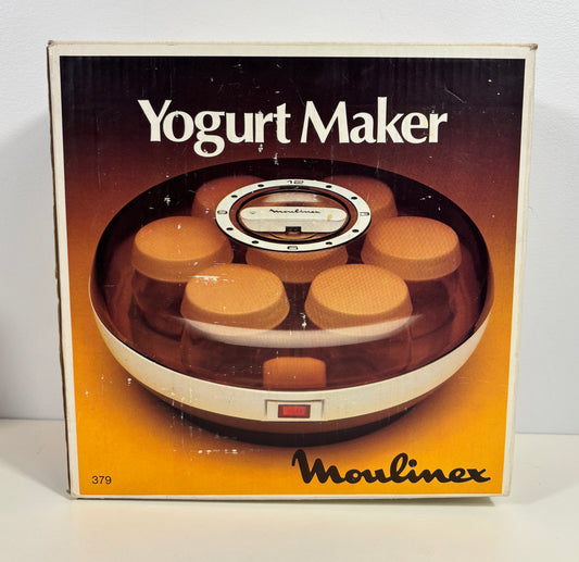 Vintage Moulinex Yogurt Maker retail box, showing the circular yogurt maker with several jars inside through a clear window, on a white background.