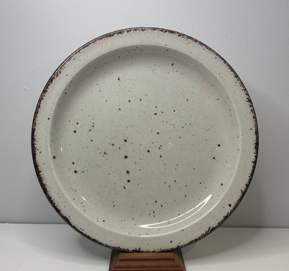 Speckled ceramic plate on a stand against a white background