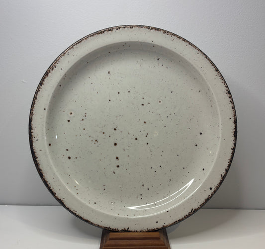 Speckled ceramic plate on a stand against a white background
