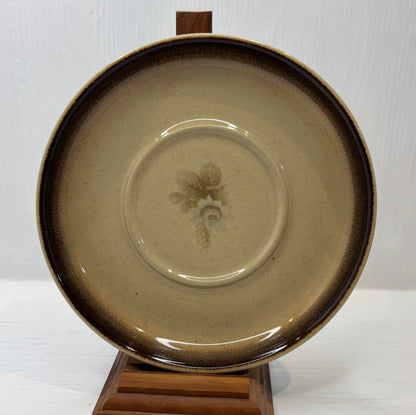 Ceramic plate with a floral design on a wooden stand against a white background