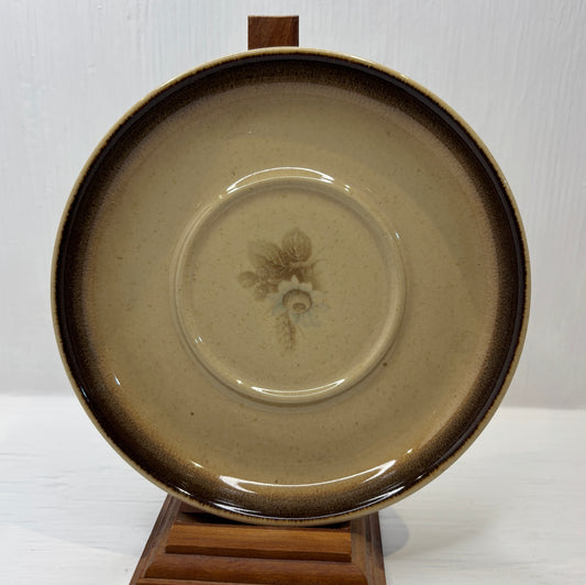 Ceramic plate with a floral design on a wooden stand against a white background