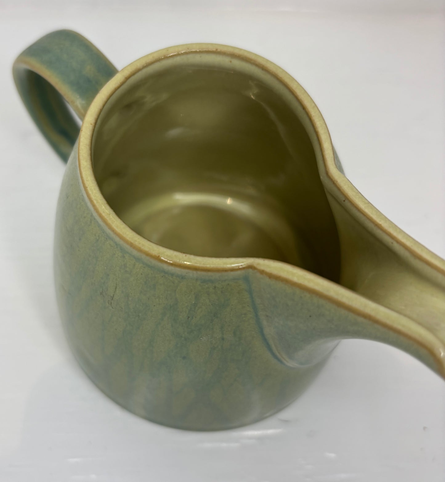 Green ceramic pitcher on a white background