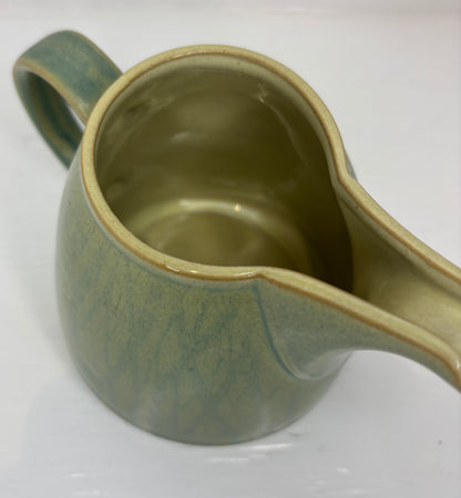 Green ceramic pitcher on a white background