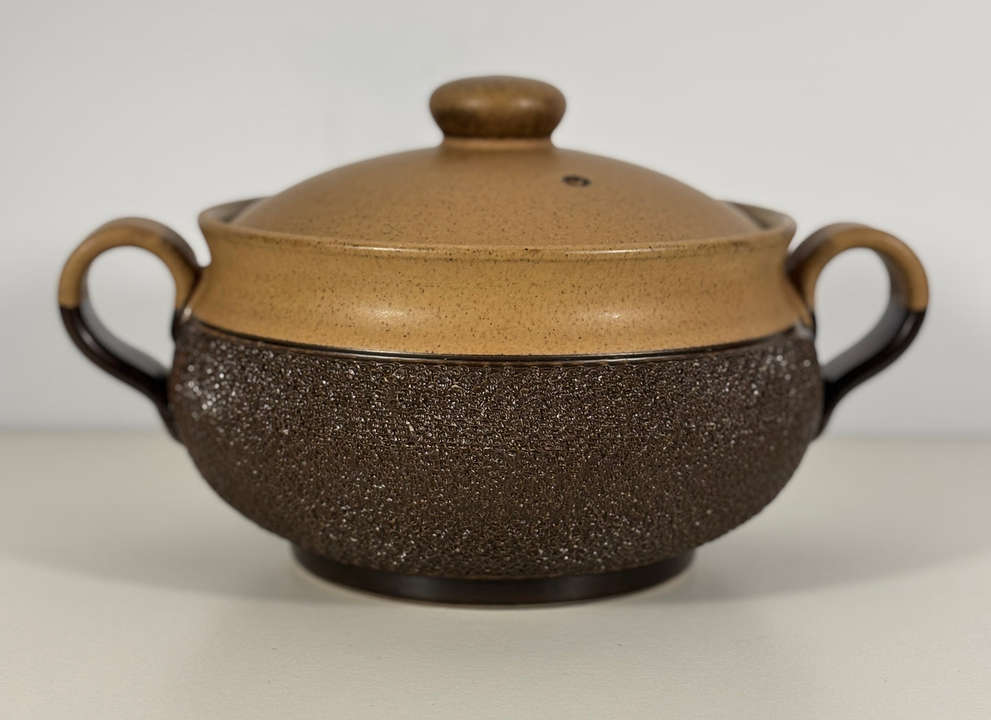 Brown ceramic pot with textured surface on a white background