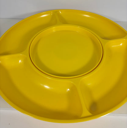 A bright yellow plastic divided plate with a central round plate that fits inside, photographed against a plain light background.