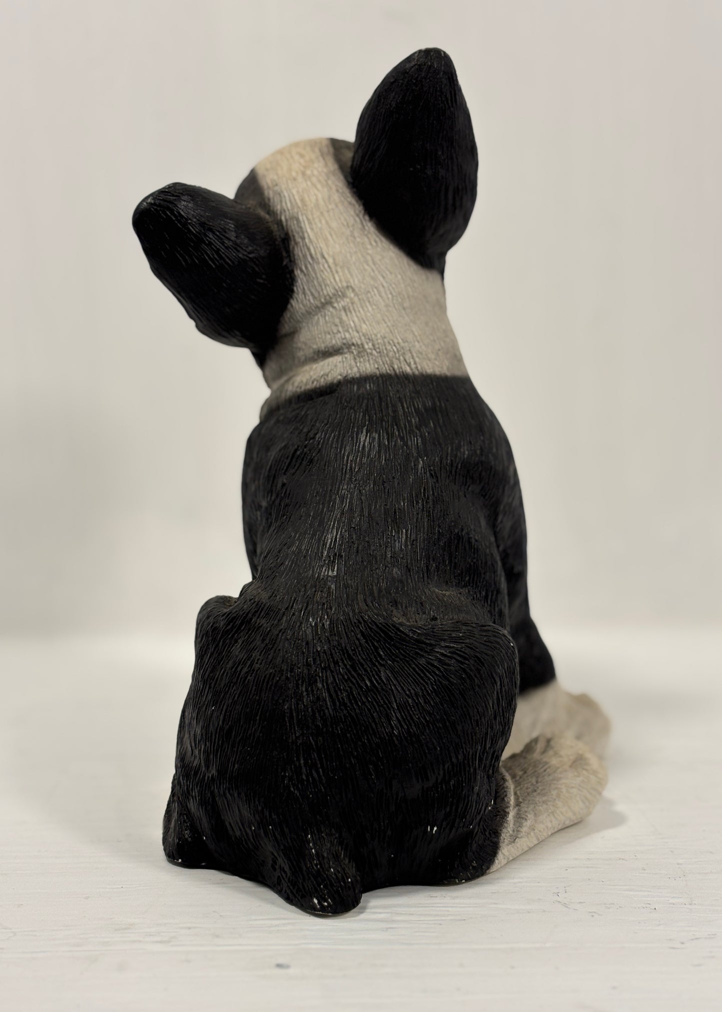 Black and white dog figurine sitting on a white background