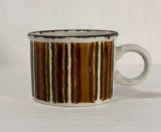 Ceramic mug with brown and black striped pattern on a white background