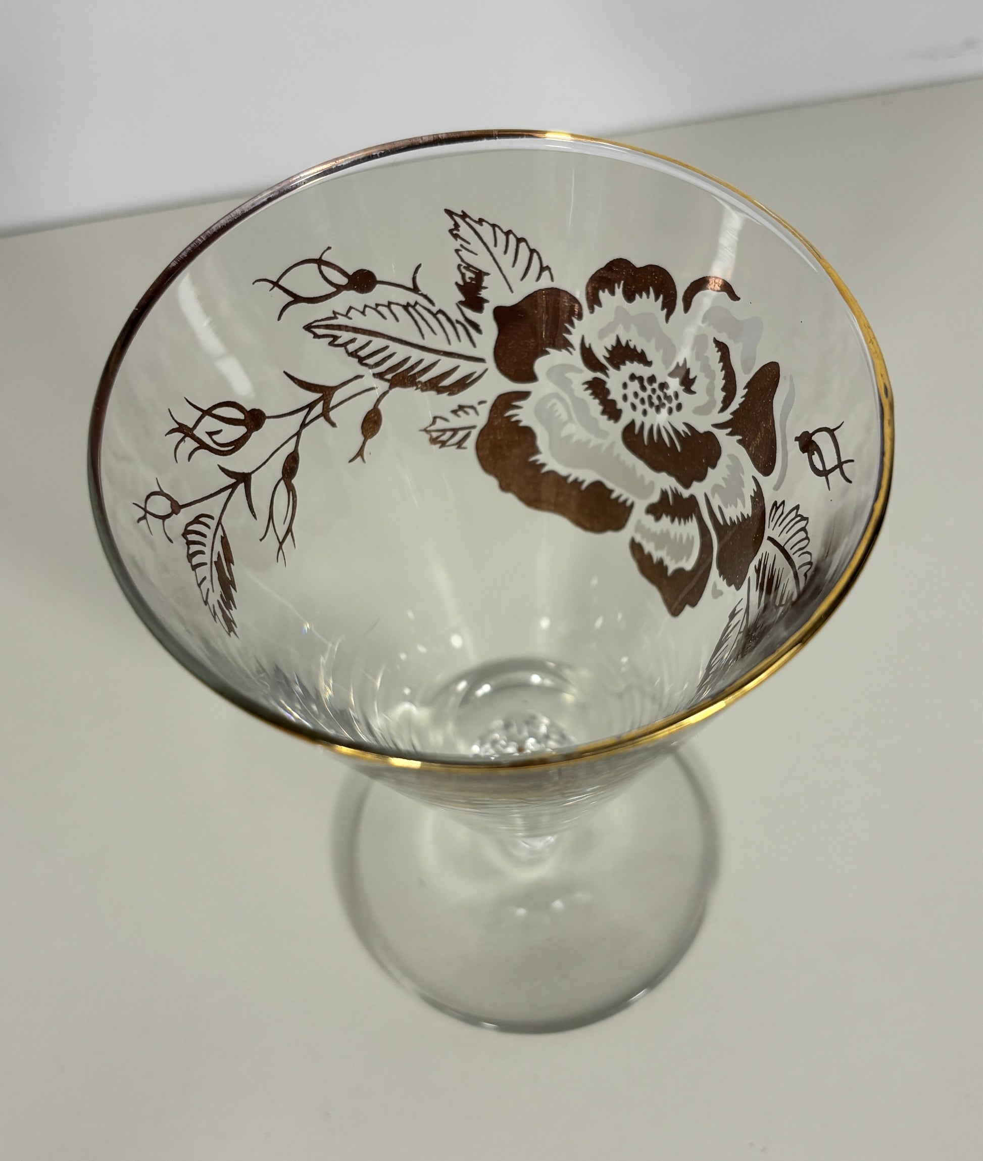 Clear glass with floral design and gold rim on a white background