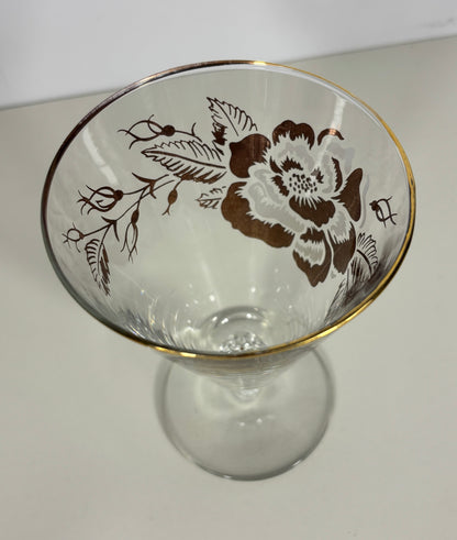 Clear glass with floral design and gold rim on a white background