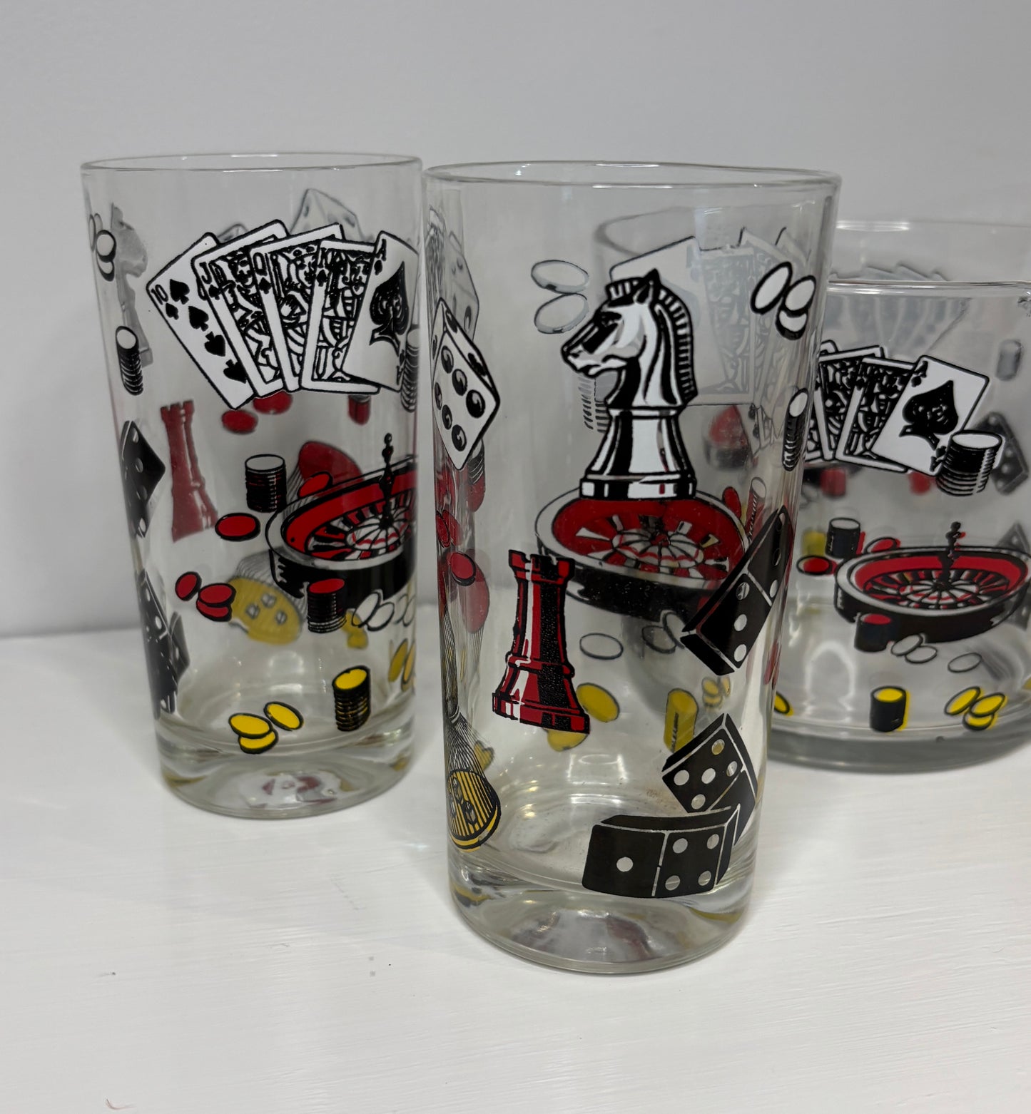 Three glass tumblers with poker-themed illustrations on a white background