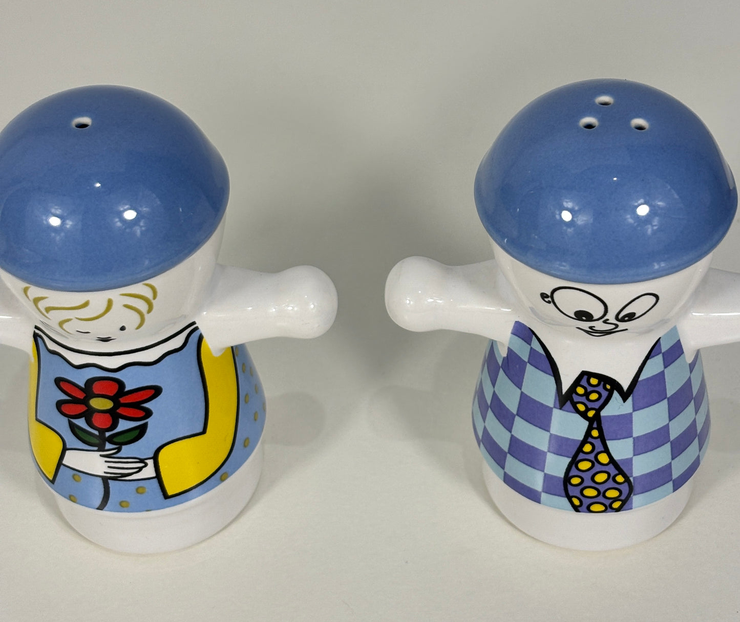 Two ceramic salt and pepper shakers with cartoon-like designs on a white background