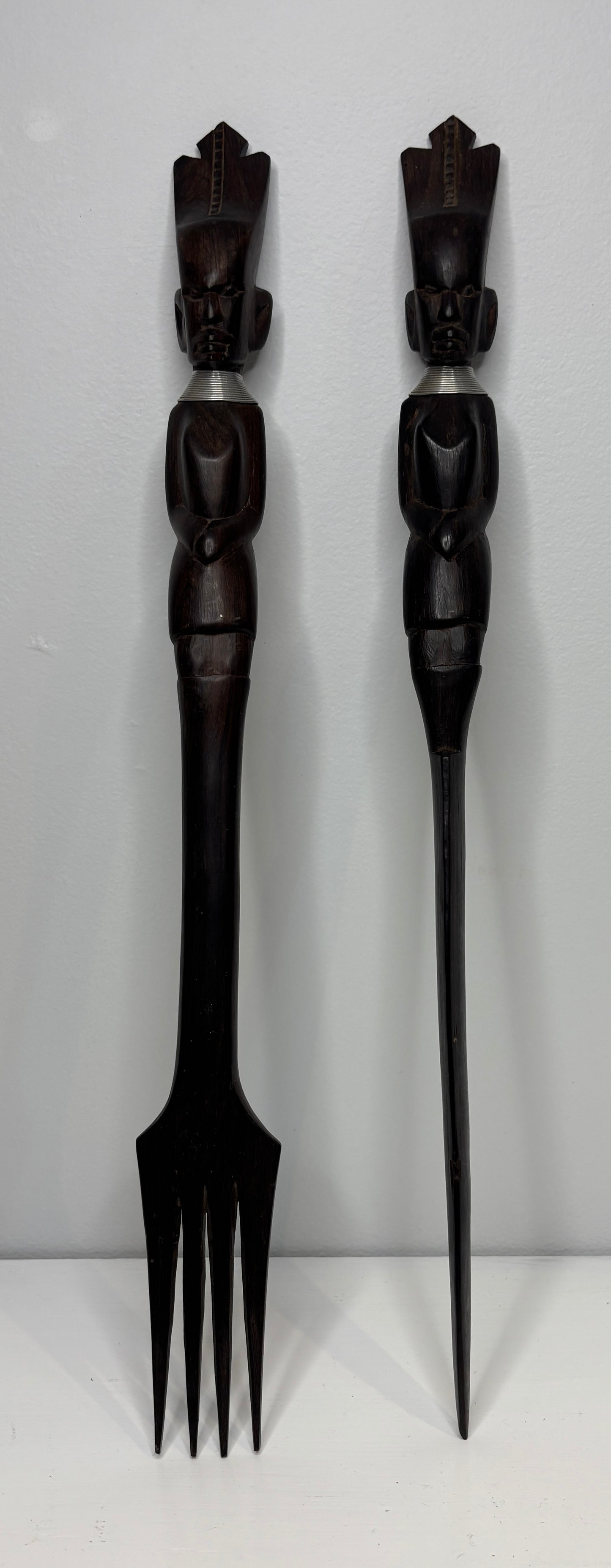Two black decorative forks with figurine handles on a white background
