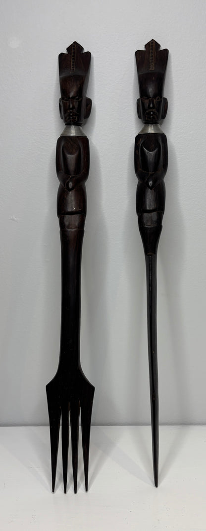 Two black decorative forks with figurine handles on a white background