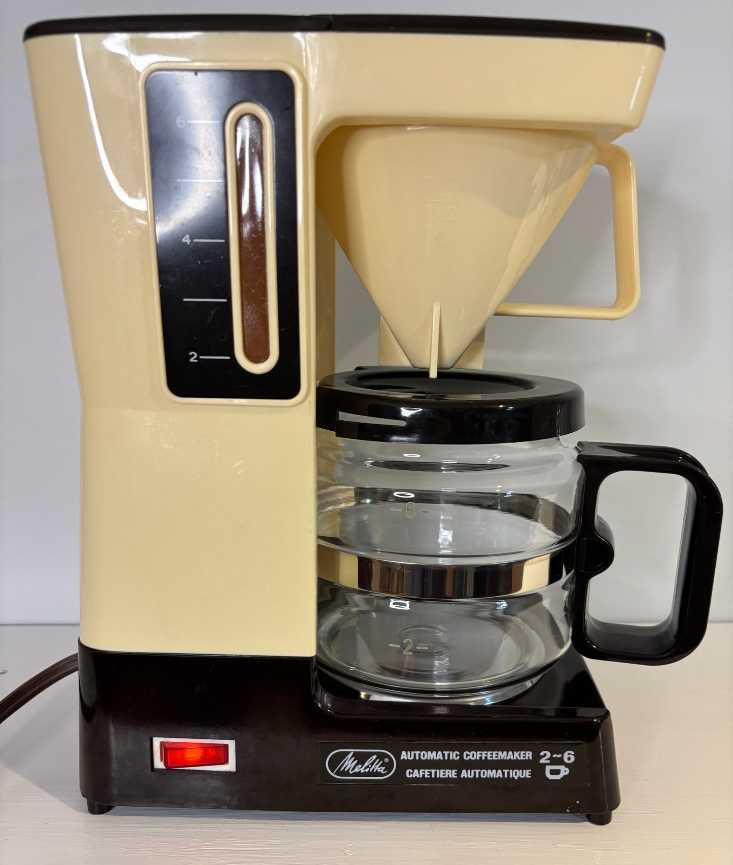 Vintage-style coffee maker with beige body and black base on a white background