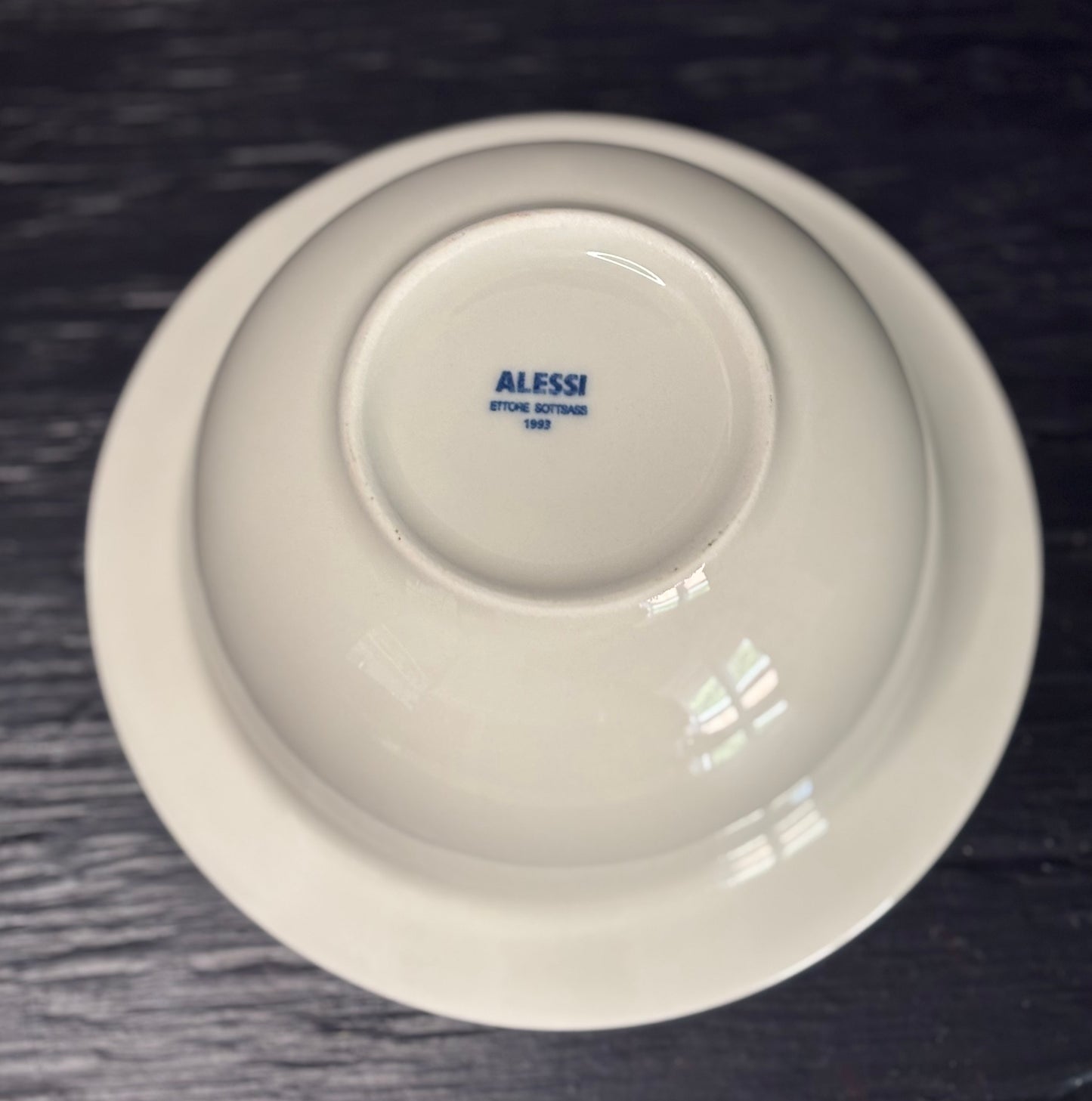 White bowl with 'Alessi' branding on a dark textured surface