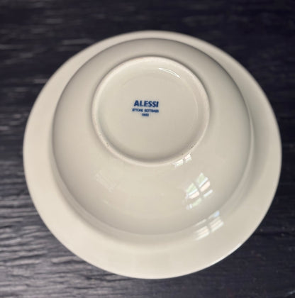 White bowl with 'Alessi' branding on a dark textured surface