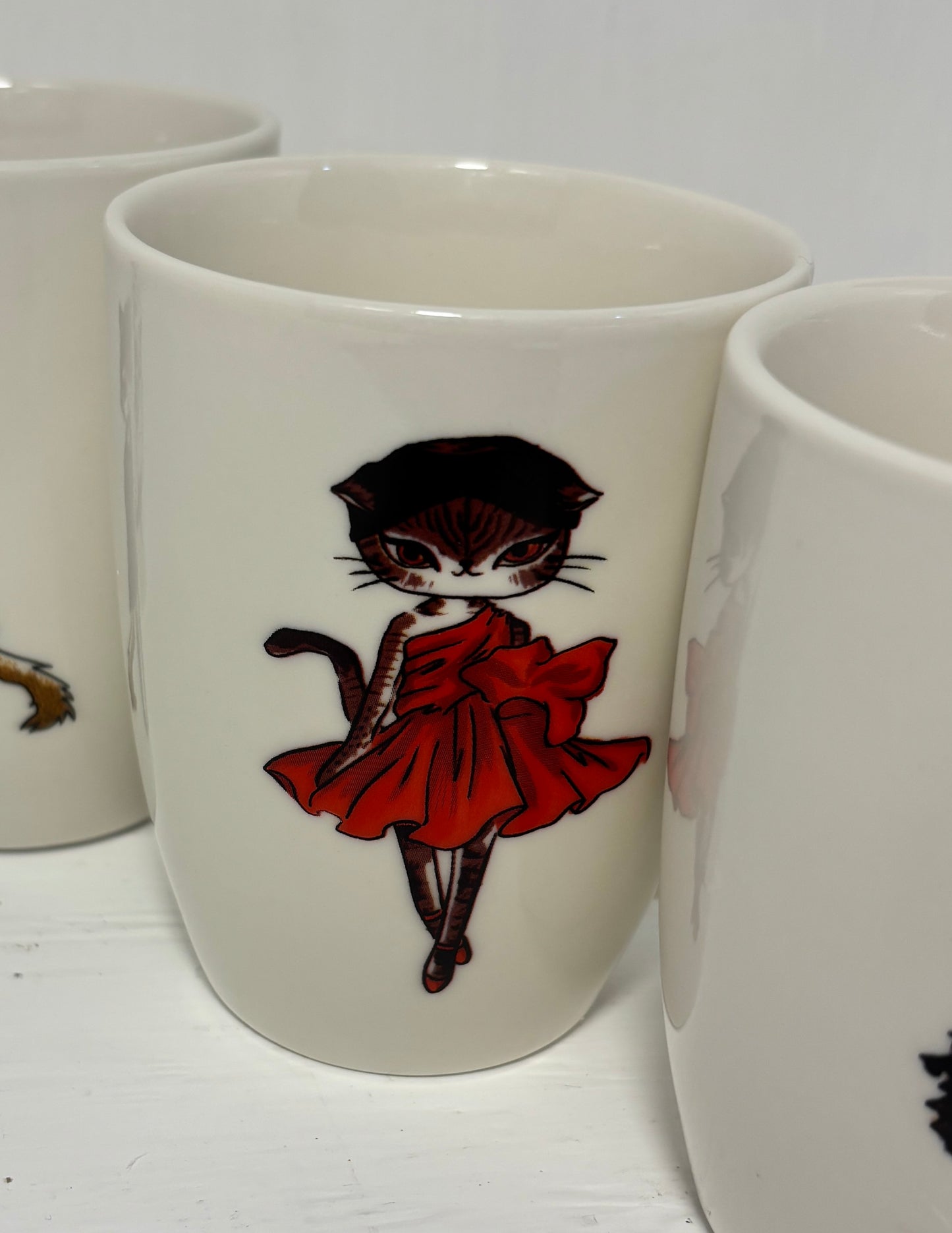 Mug with a cat in a red dress design on a white surface
