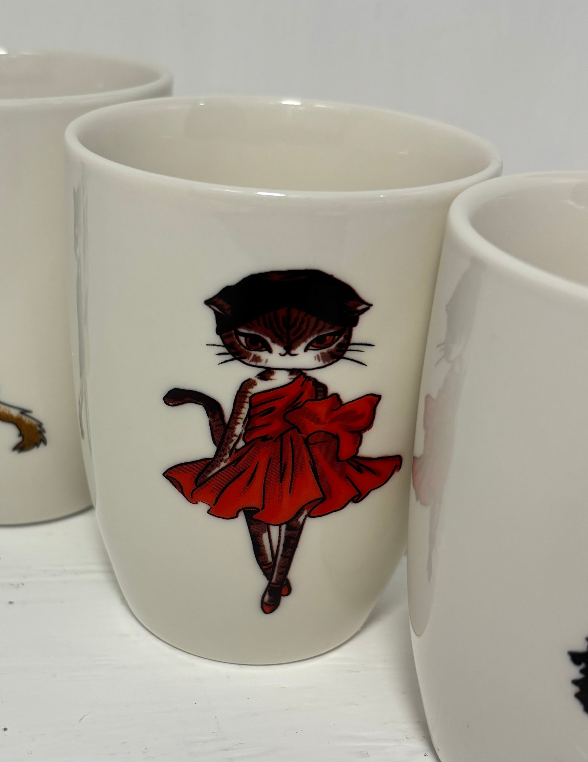 Mug with a cat in a red dress design on a white surface