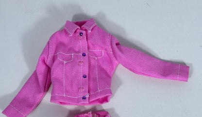 A pink doll jacket with white contrast stitching and purple buttons, laid flat on a light gray background.