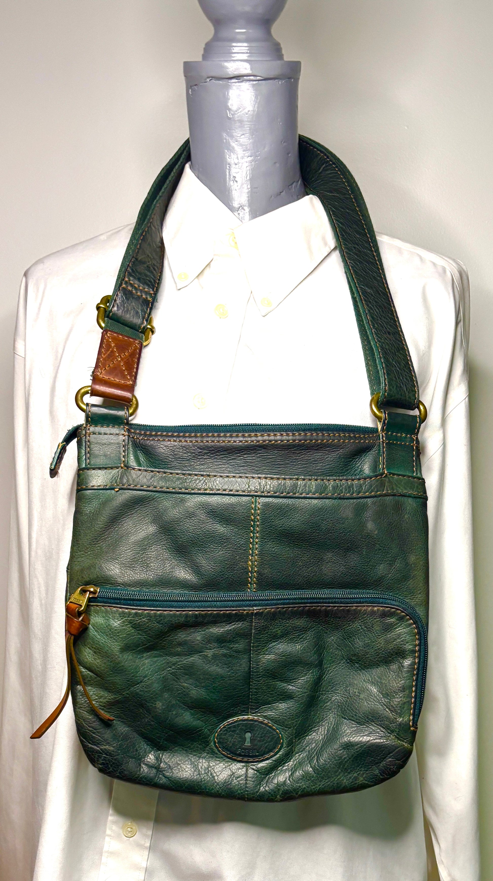 Green leather shoulder bag on a mannequin with a white background