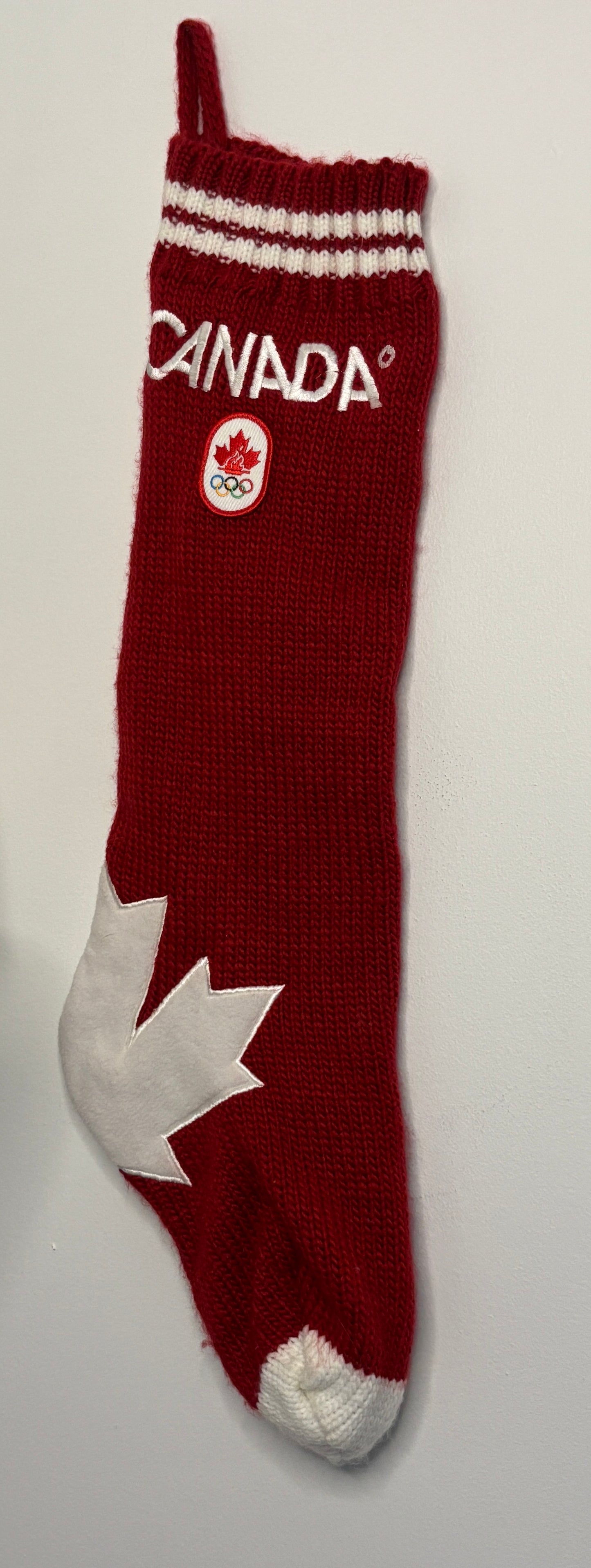 Red sock with white maple leaf and 'Canada' text on a light gray background