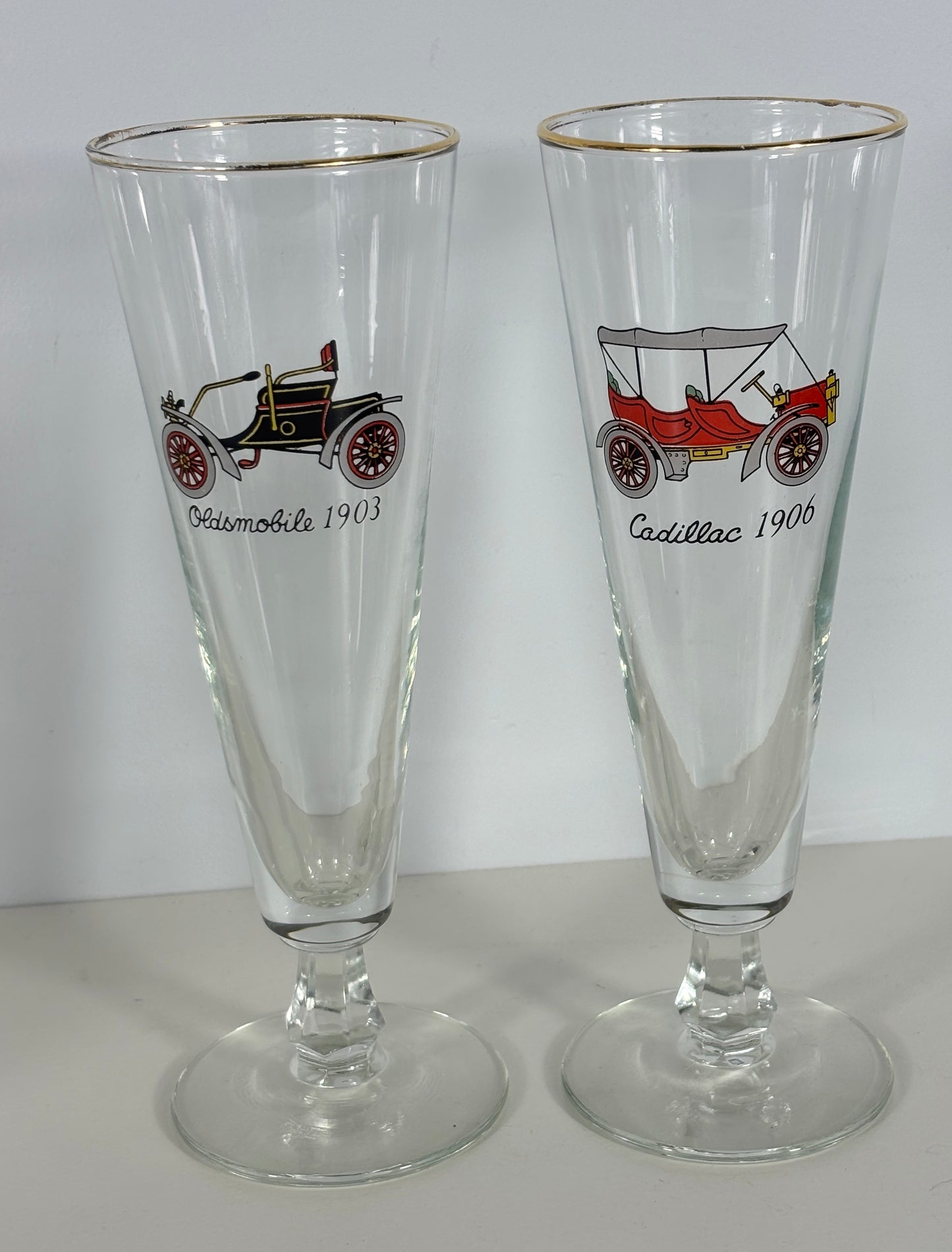Two glass tumblers with vintage car illustrations and text on a white background