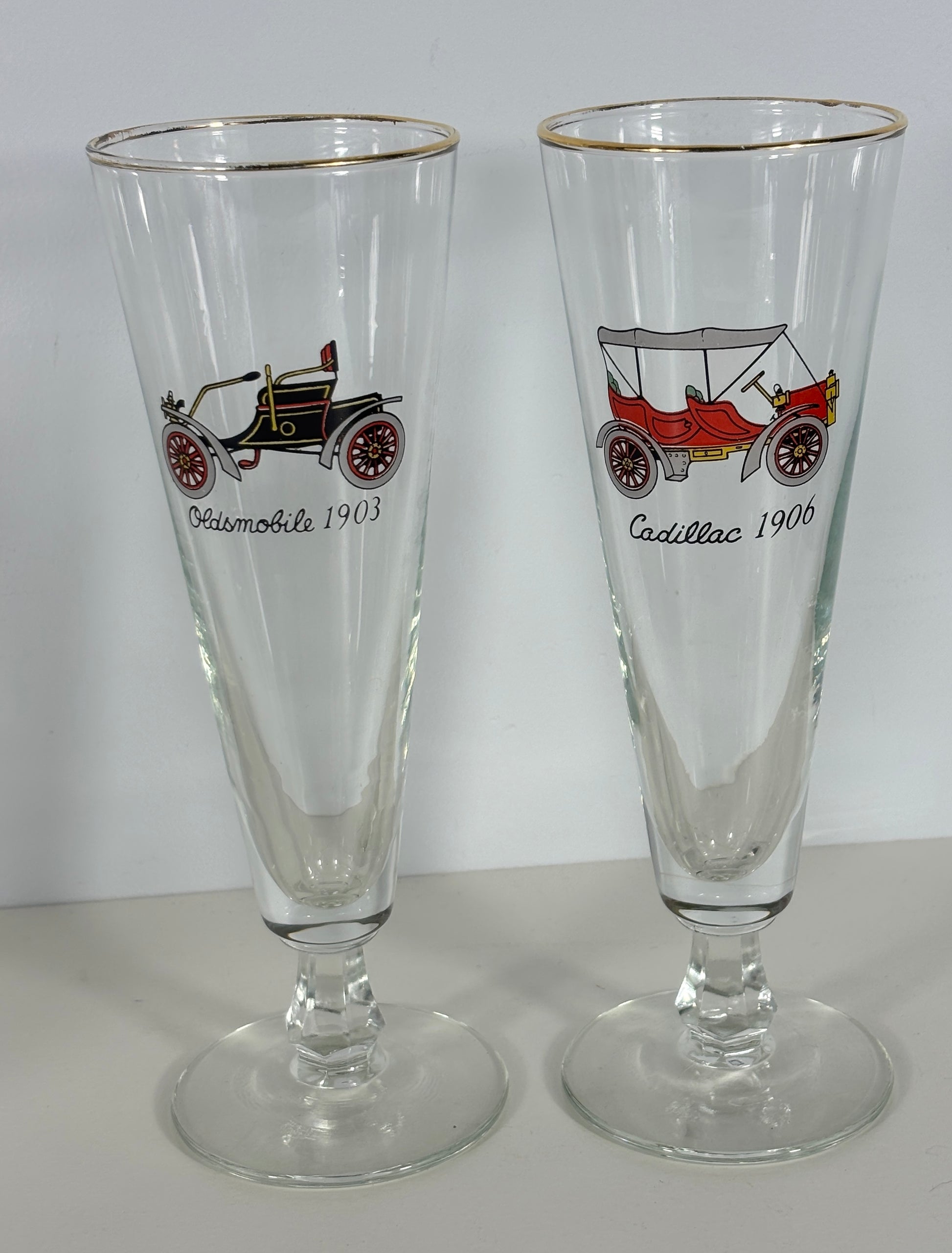 Two glass tumblers with vintage car illustrations and text on a white background