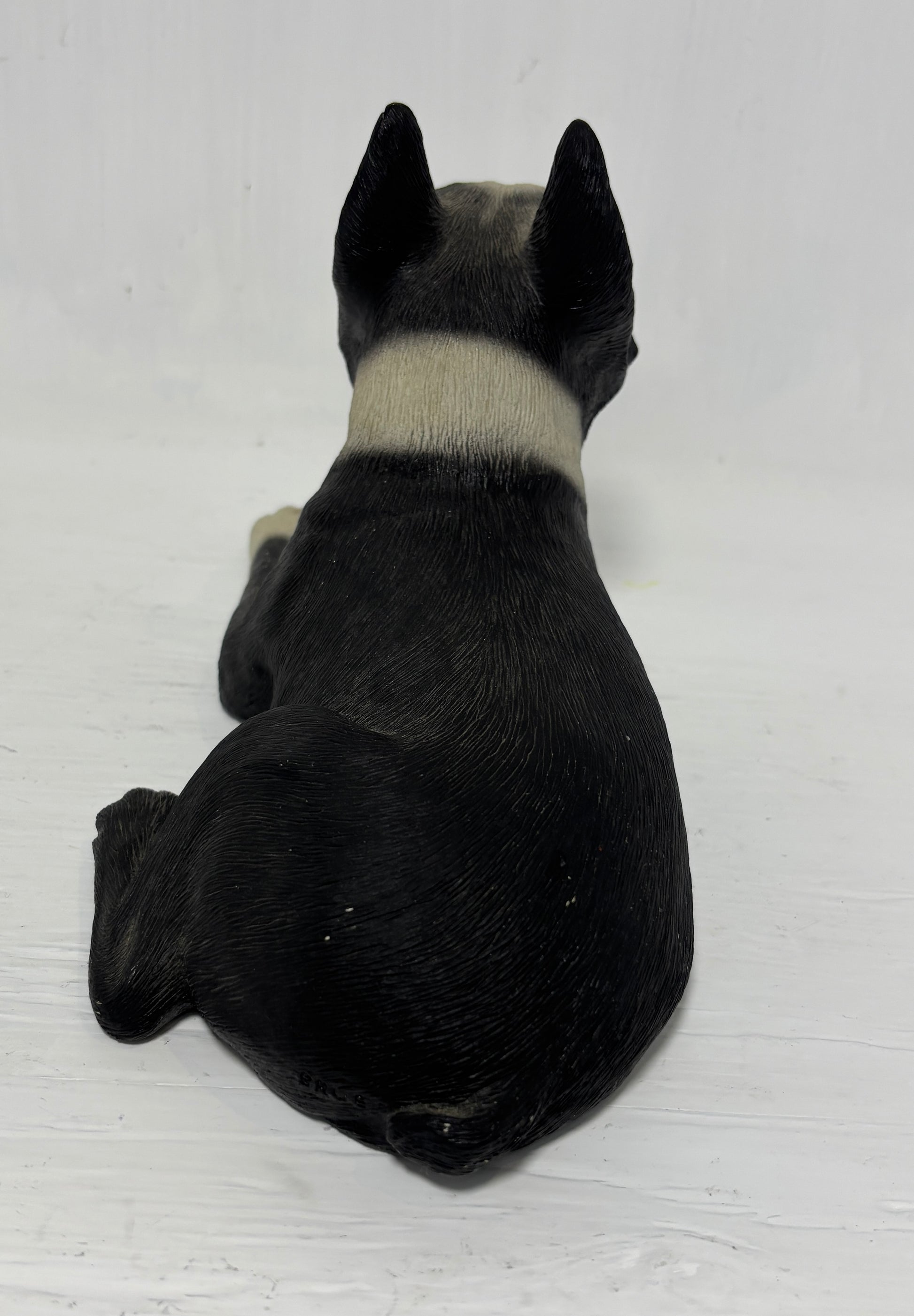 Black and white dog figurine on a light wooden surface