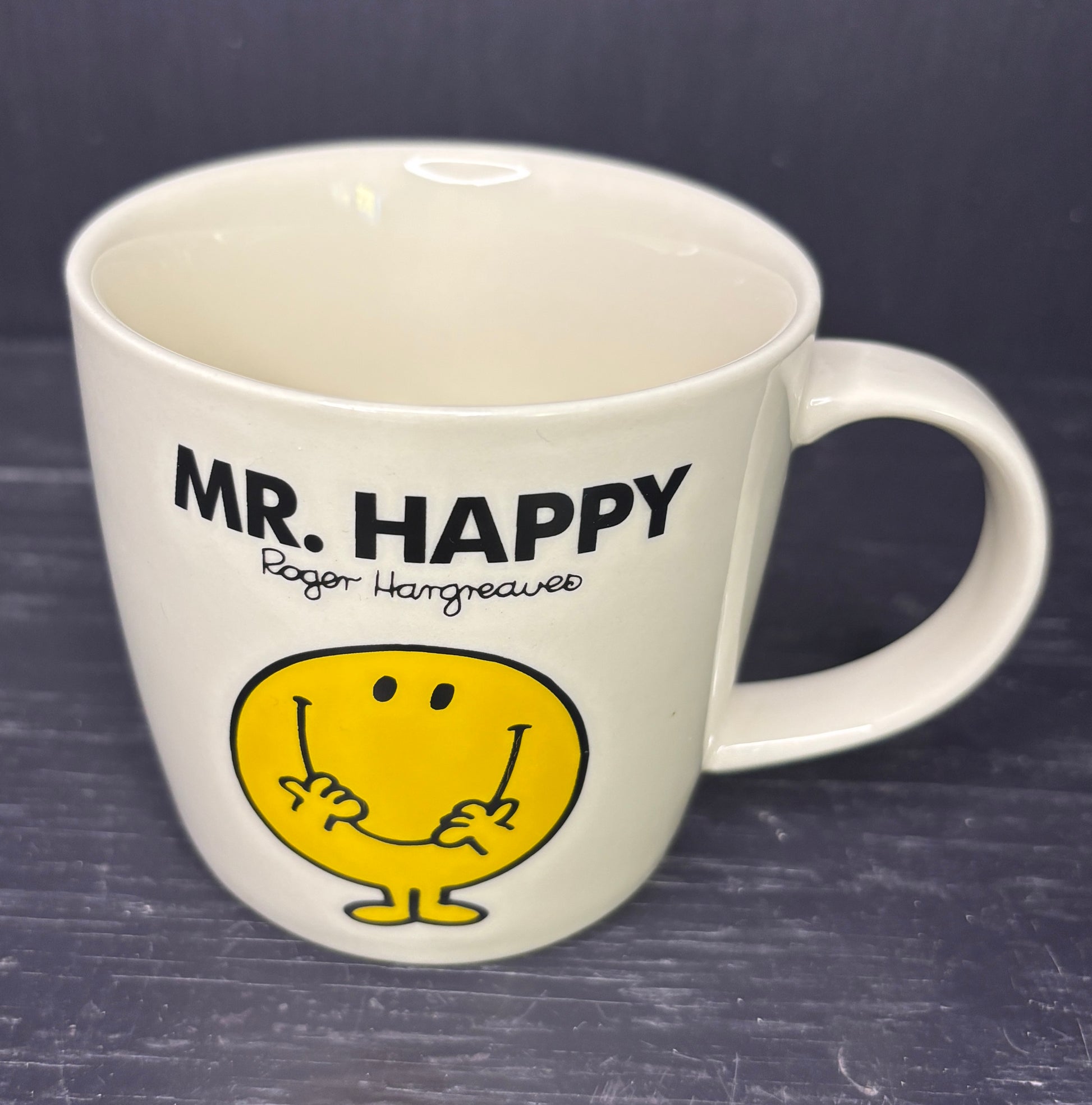 White mug with 'MR. HAPPY' and a yellow character on a dark background