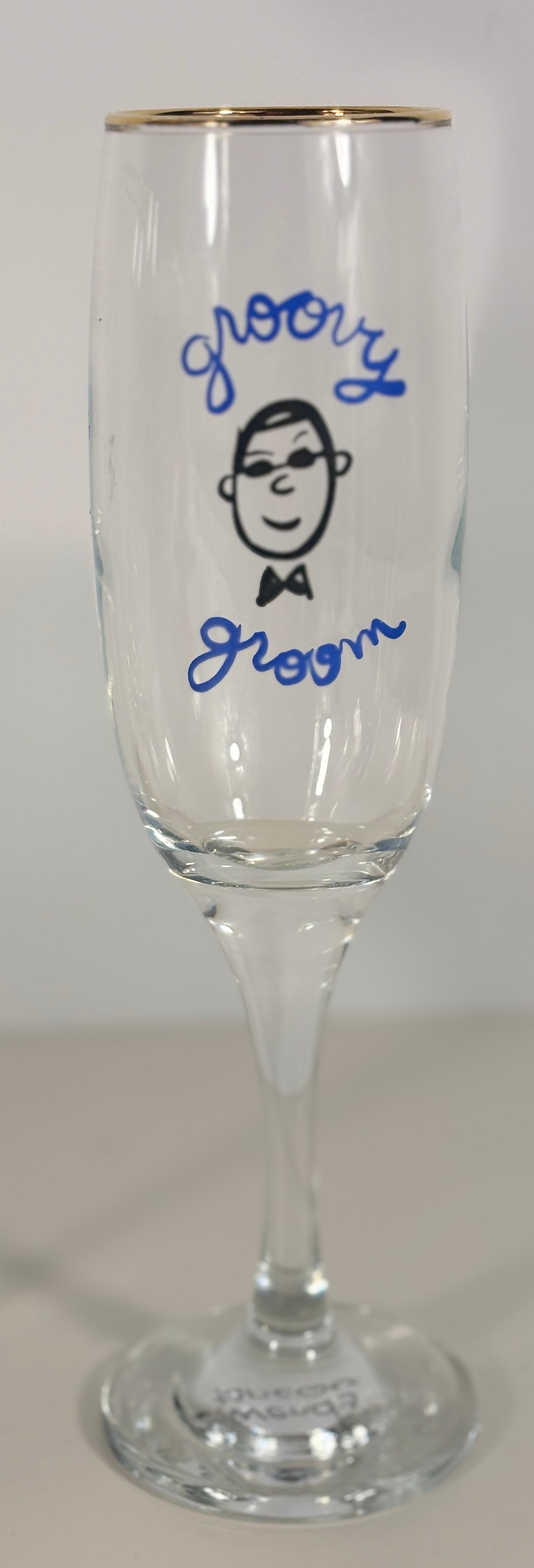 Clear glass with 'groom' and a face drawn on it, against a white background