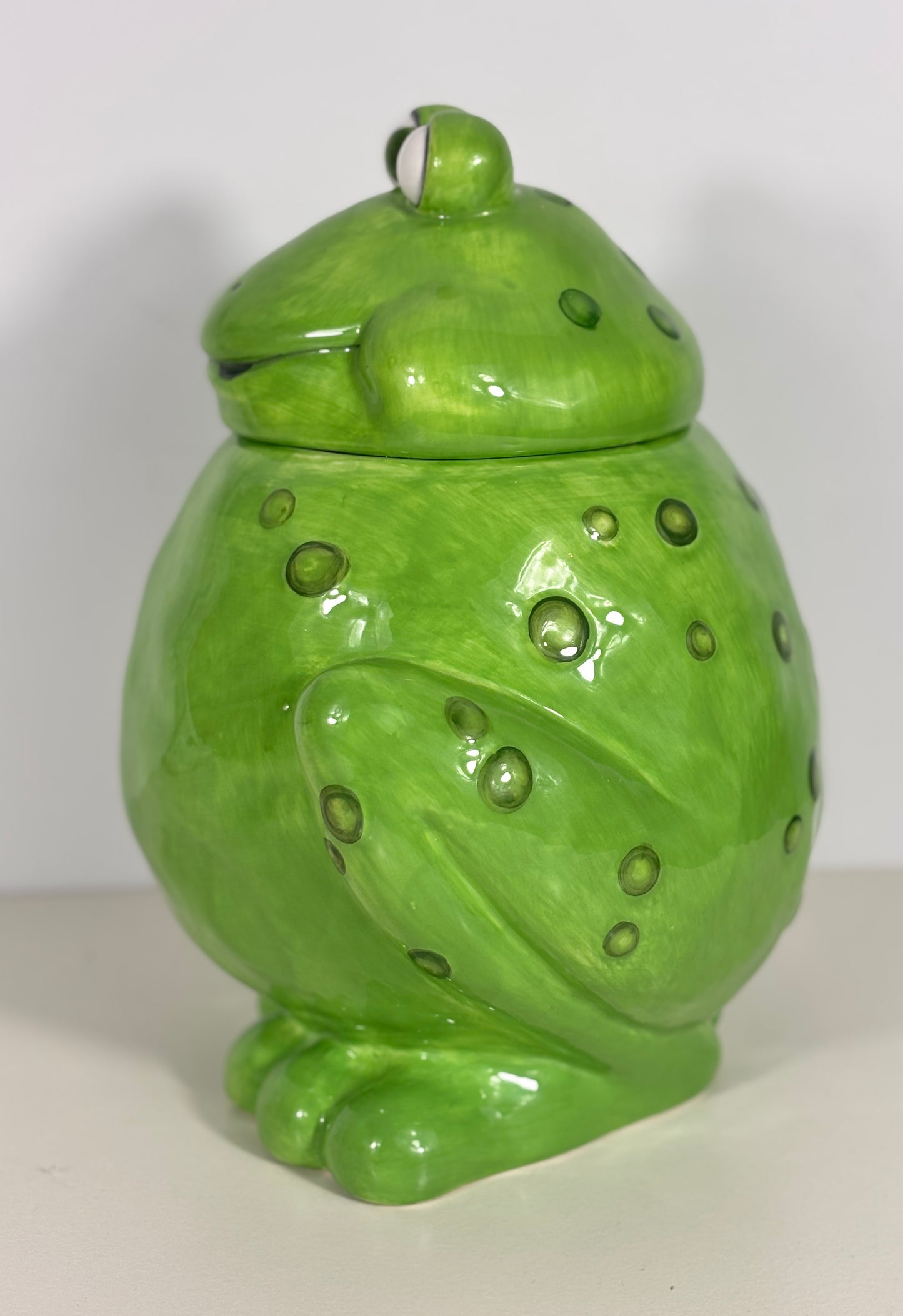 Green ceramic frog-shaped jar with a lid on a white background