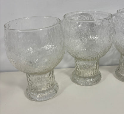 Three clear textured glass goblets with flared bases, shown on a plain light background.