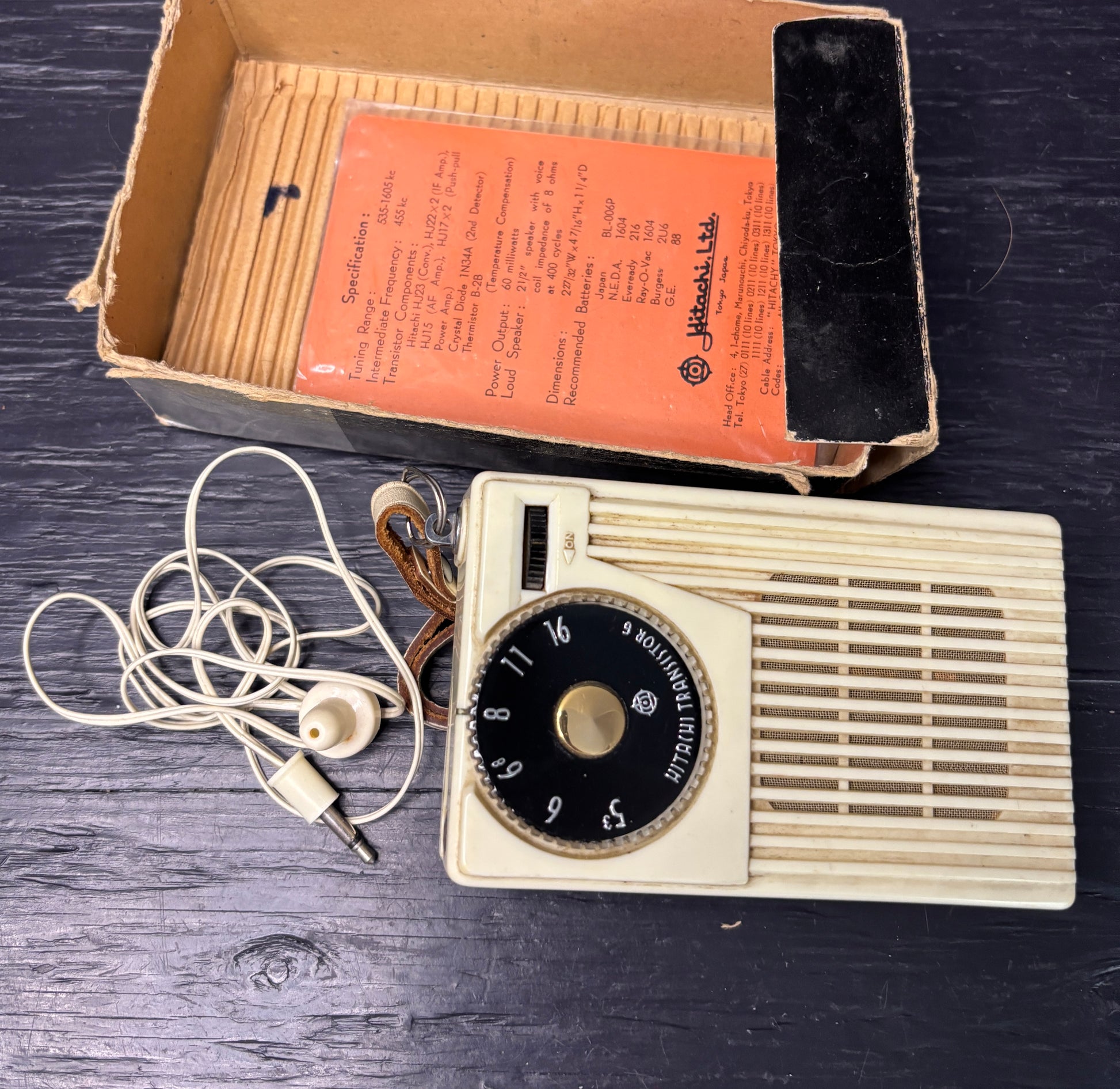 Vintage radio with earphones and manual on a wooden surface