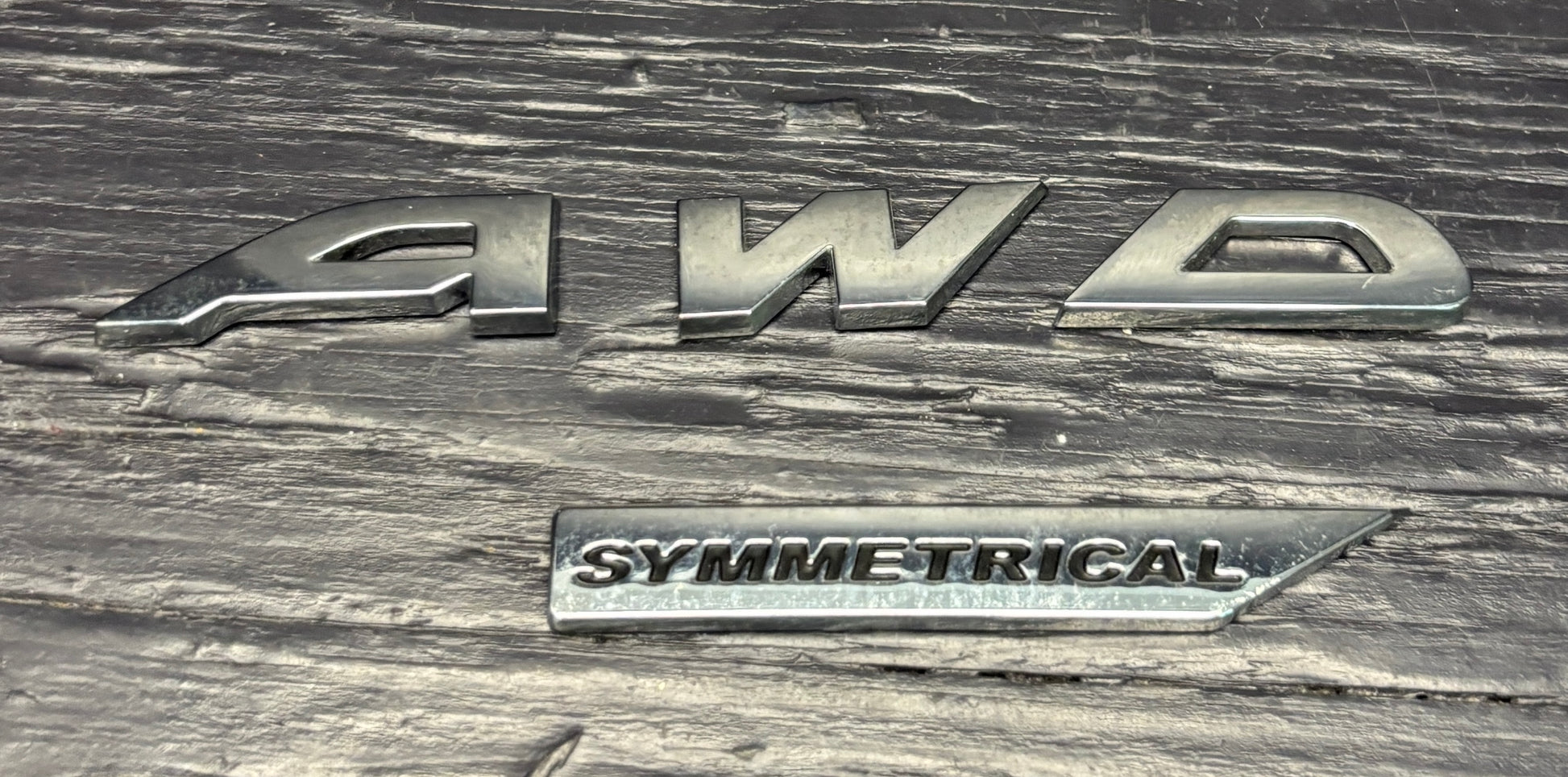 Silver '4WD Symmetrical' badge on a textured metal surface