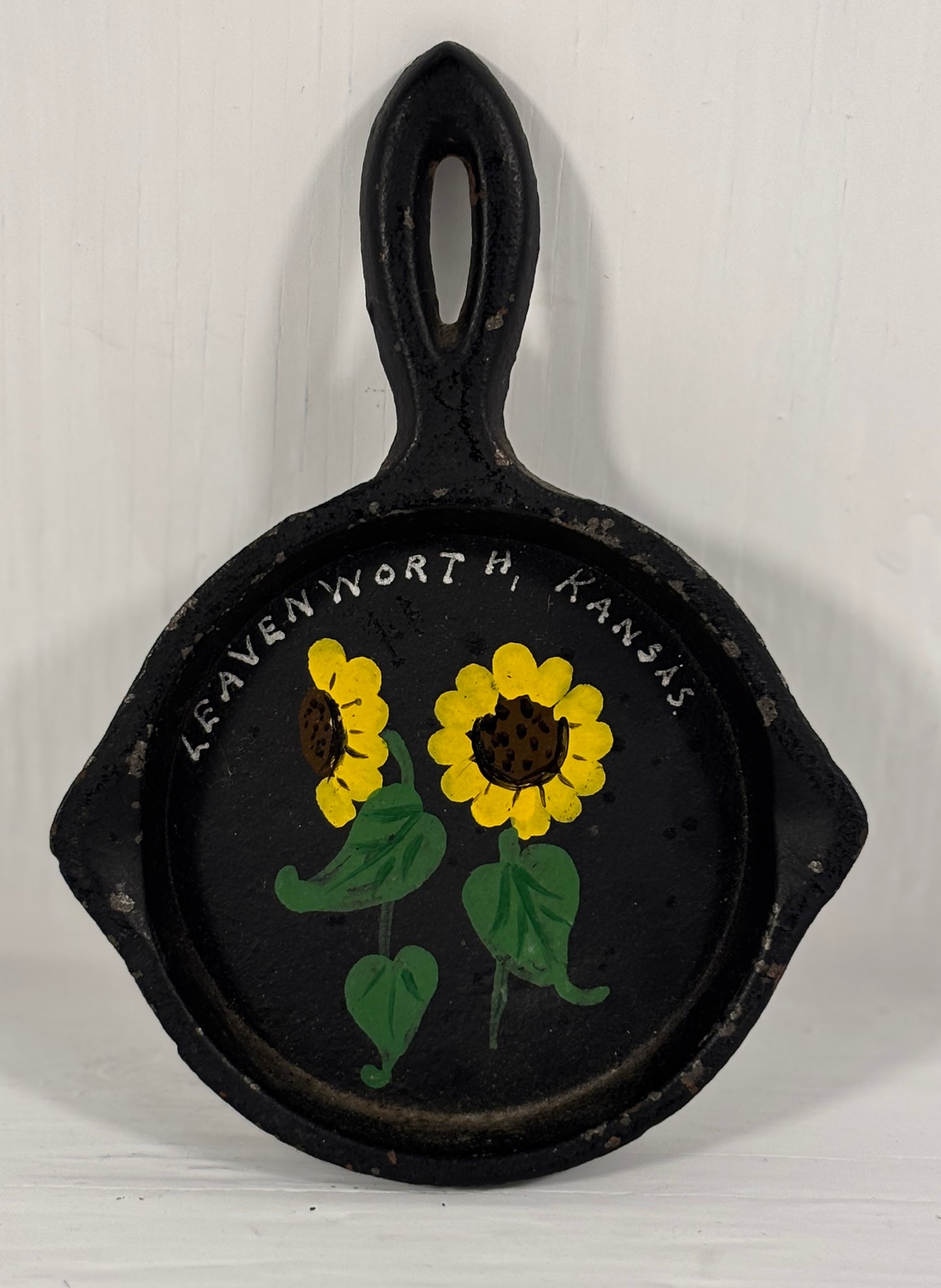 Decorative cast iron skillet with sunflowers and 'Leavenworth, Kansas' text on a white background