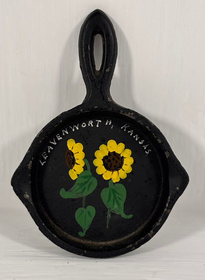 Decorative cast iron skillet with sunflowers and 'Leavenworth, Kansas' text on a white background