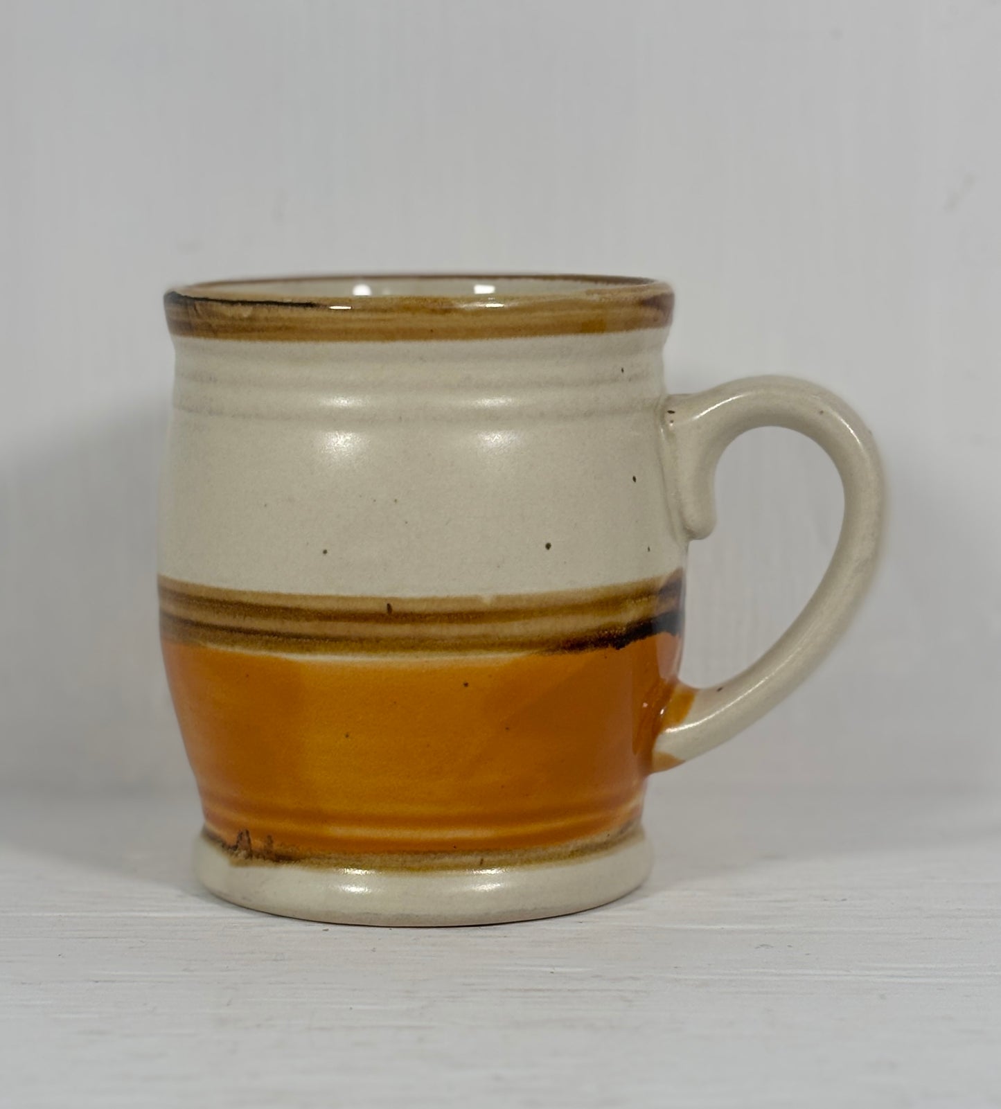 Ceramic mug with brown and beige stripes on a white background