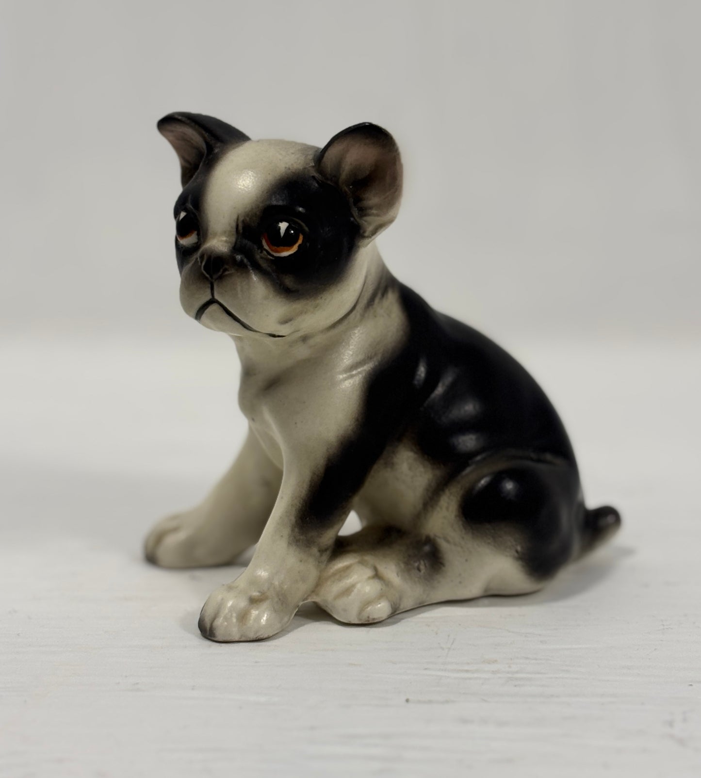Porcelain figurine of a black and white dog on a light gray background