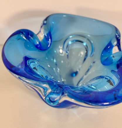 Blue glass bowl with wavy design on a beige background