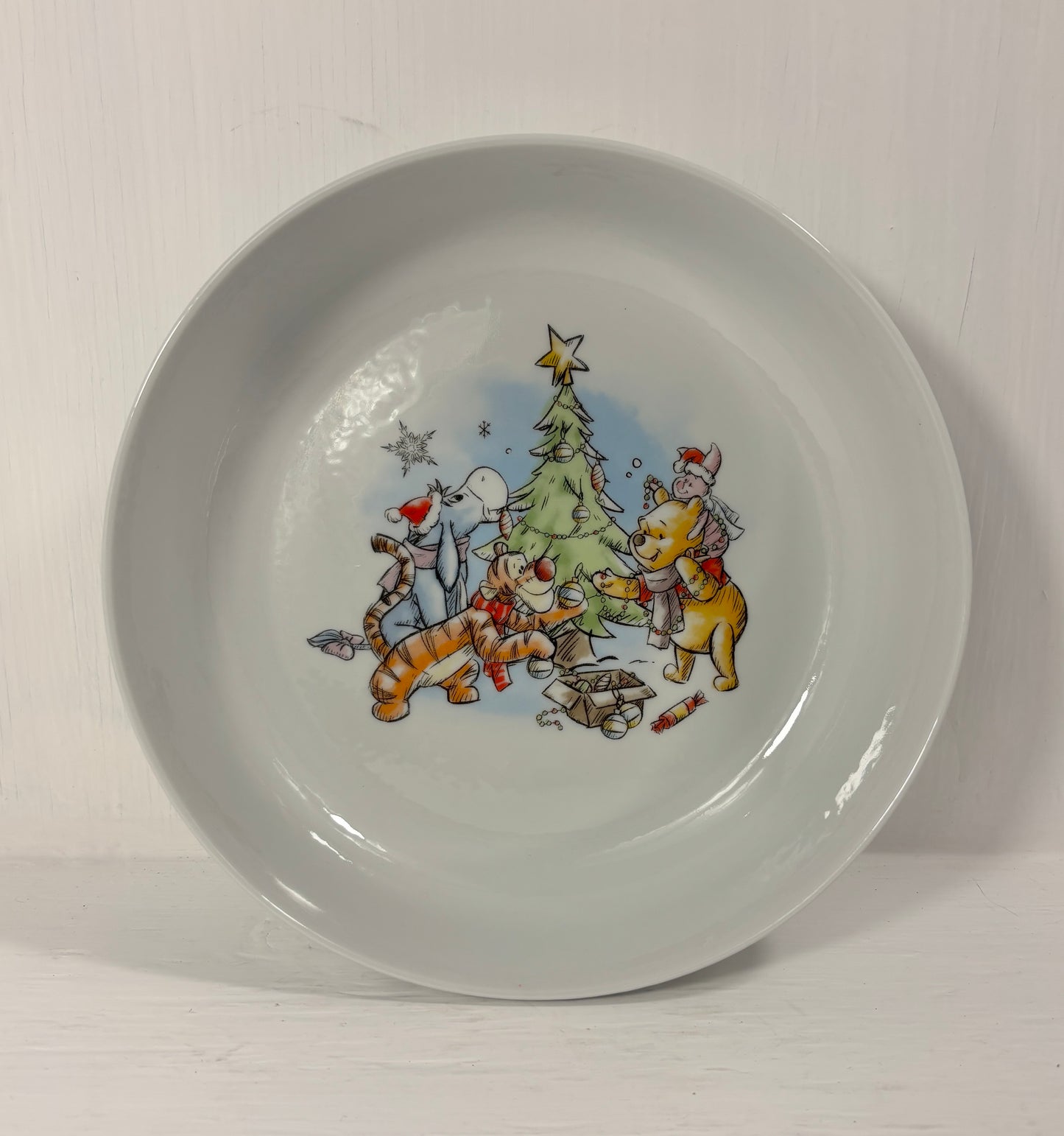 Children's bowl with winie the pooh cartoon characters around a Christmas tree on a white background